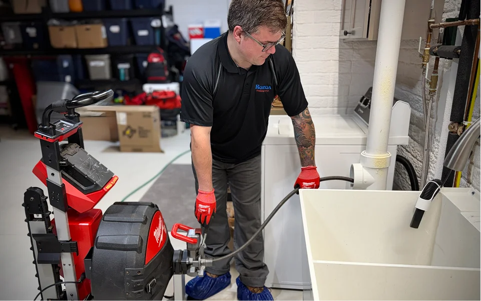 Rozga Plumbing Corp technician using drain cleaning equipment on a utility sink in Southeastern Wisconsin