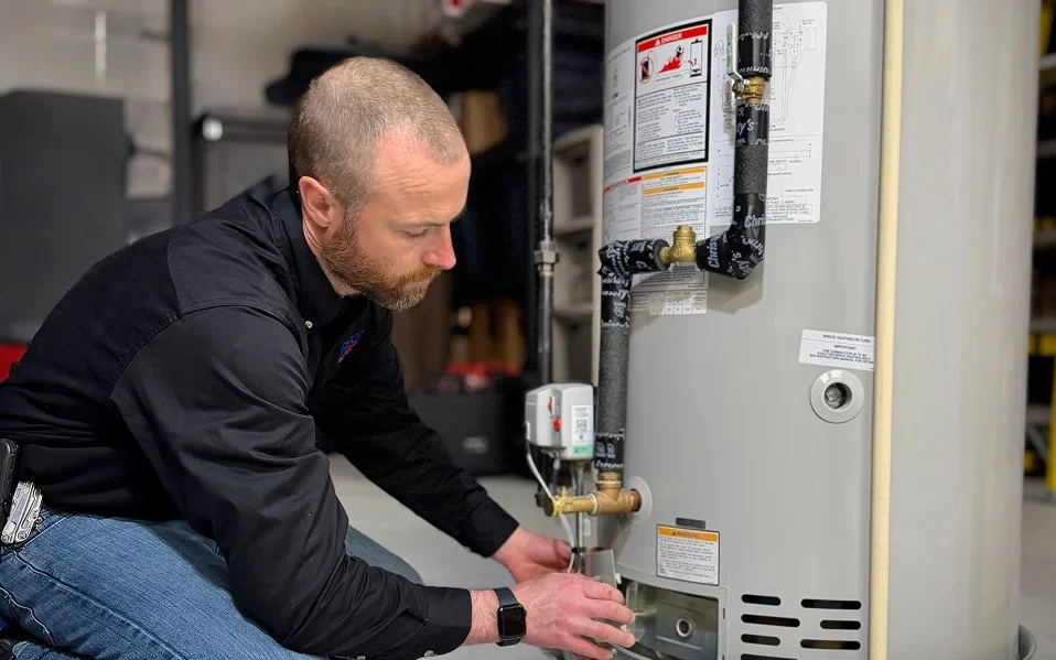 Rozga Plumbing Corp technician inspecting a residential water heater in Southeastern Wisconsin